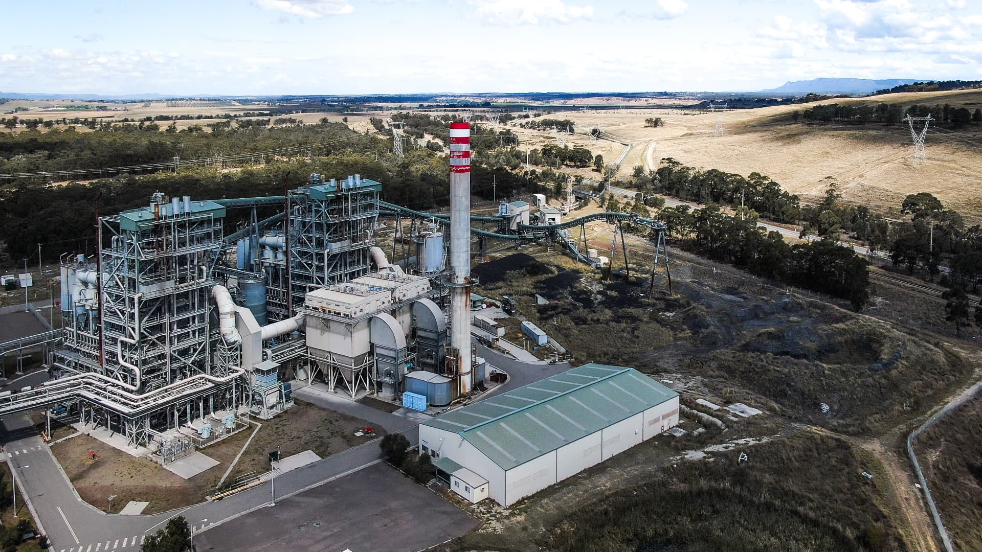 Aerial view of Redbank Power Station in the Hunter Valley with its red-and-white stack and fuel conveyor